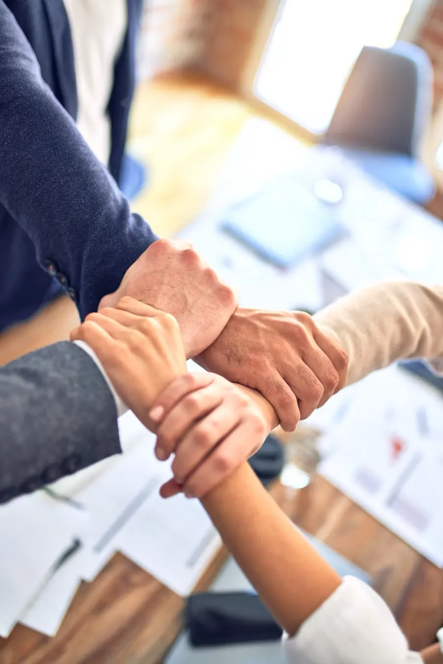 Support team putting hands together in collaboration over important paperwork
